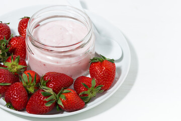 fruit yogurt in a glass jar and fresh strawberries on white background