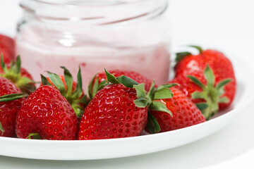 fruit yogurt in a glass jar and fresh strawberries, closeup