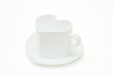 White mug in the shape of a heart on a saucer on a white background.