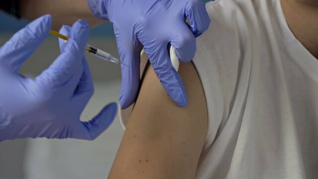 Hands of a nurse giving a vaccine to a patient. Wearing protective latex gloves. Close-up.