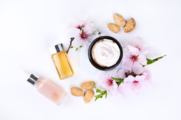 Jar with cream, oil and essence on a light background. Hand care lotion with almond oil and...
