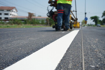 Technicians are marking a traffic line on a paved road.
