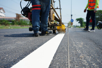Fototapeta na wymiar Technicians are marking a traffic line on a paved road.