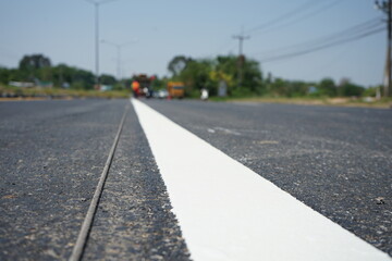 Technicians are marking a traffic line on a paved road.