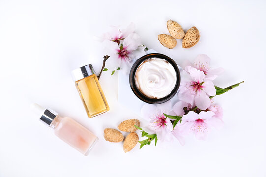 Jar With Cream, Oil And Essence On A Light Background. Hand Care Lotion With Almond Oil And Vitamins. Body Skin Health And Beauty. Cosmetics And Natural Almond Flowers. Copy Space . Mockup