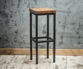 a sturdy high bar stool made of wood and metal in the loft or industrial style in the interior....