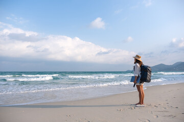 A female traveler holding laptop computer while walking on the beach