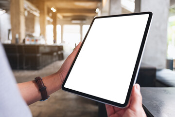 Mockup image of a woman holding digital tablet with blank white desktop screen in cafe
