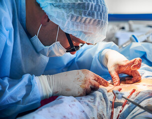 Male doctor placing sutures following an abdominoplasty procedure.