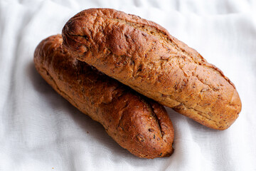 two freshly baked rye bread rolls on a white cloth napkin