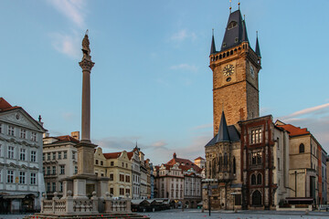 Fototapeta premium Old Town Square in Prague, Czech Republic. Empty city during sunrise without people surrounded by historical, gothic style buildings and the famous Astronomical Clock Tower.Beautiful urban scene