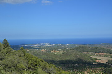 Naklejka premium View from the top of the mountain to the beautiful landscape below. View from the mountain to the sea. Green plain in the rays of the summer sun. Mountain walk.