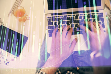 Double exposure of man's hands typing over laptop keyboard and forex chart hologram drawing. Top view. Financial markets concept.