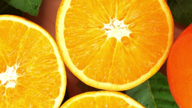 Orange fruit with slices closeup, Top view Rotate fruits, Sweet orange fruit with green leaves in the garden.