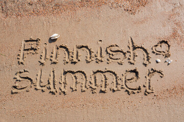 Words Finnish summer with small heart handwritten on a sandy beach