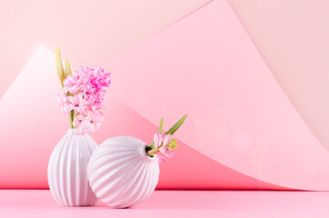 Spring hyacinth flowers in white ceramic vases in elegant pink geometric space with sunbeam, sun flare, modern springtime background. Festive backdrop for 8 march.