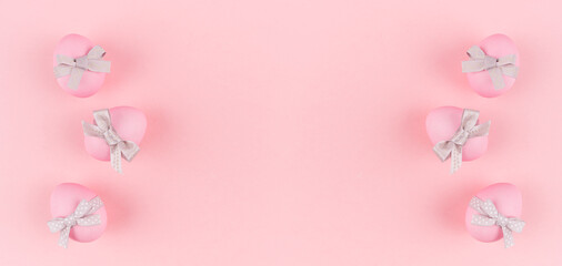 Fototapeta na wymiar Festive easter banner - pink easter eggs with silver bow as border on pastel pink backdrop.
