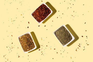 Collection of three spices on ceramic white bowl on yellow background