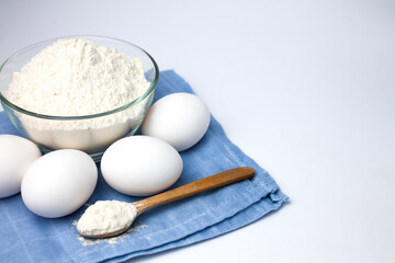 Ingredients for dough. Flour and eggs on the white background. Close-up. Copy space.