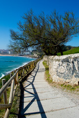 Fototapeta na wymiar Camino o paseo cerca de la costa en Santander. Camino de piedra con barandilla de madera