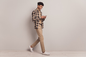 Profile photo of guy hold telephone walk wear checkered shirt turtleneck pants footwear isolated grey color background