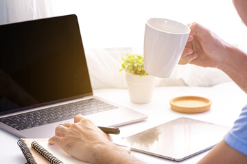 Businessman drinking coffee working and laptop on home office workspace