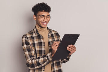 Photo portrait of young boy in casual clothes writing on clipboard interview smiling isolated on grey color background
