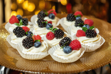 Meringue dessert with blueberries and currants on pink background