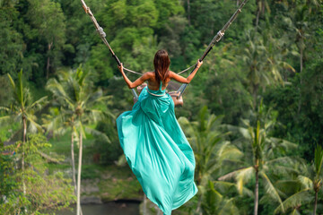 Woman in long turquoise dress swinging in the jungle, Bali - obrazy, fototapety, plakaty