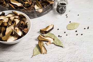 On the gray table is a plate of dried porcini mushrooms, scattered mushrooms and seasonings for...
