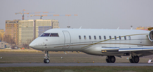 Obraz premium A twin-engine private jet drives along the taxiway behind an airfield escort vehicle