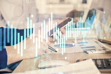 Double exposure of man's hands holding and using a digital device and forex graph drawing. Financial market concept.