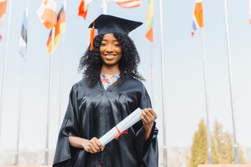 Young female african american student with diploma poses outdoors.