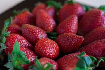 Plato de fresas negro sobre madera