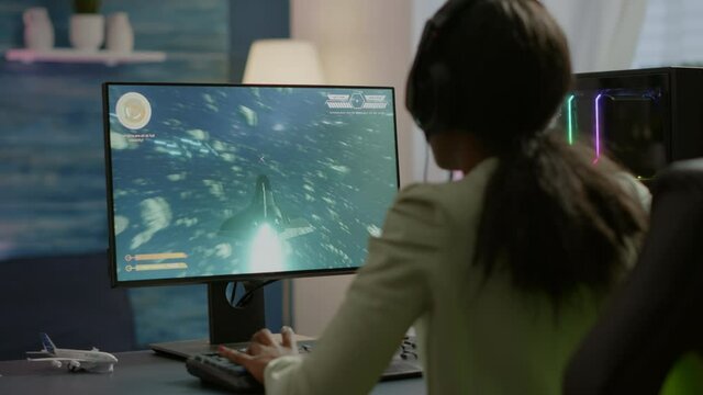 African pro eSport gamer with headset playing in competitive video games on cyber gaming tournament. Virtual championship in cyberspace, esports player performing on RGB powerful personal computer