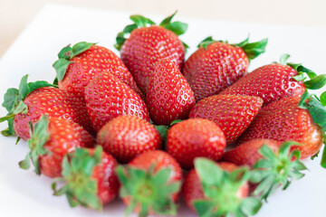 Plato de fresas sobre fondo blanco y madera