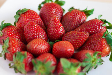 Plato de fresas sobre fondo blanco y madera
