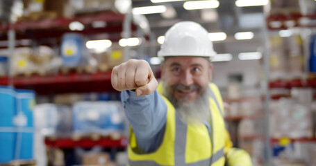 Portrait of funny senior industrial worker in uniform posing as superhero in warehouse
