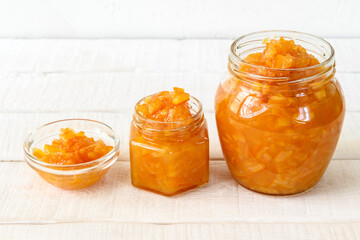 Glass jars with orange jam on a white wooden table