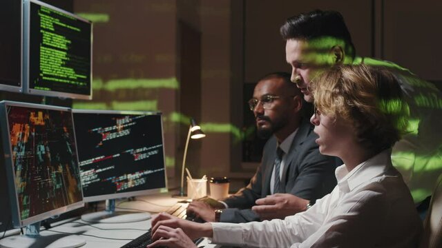 Side view shot footage of multi-ethnic information security department specialists checking computer codes to find out hacker attack