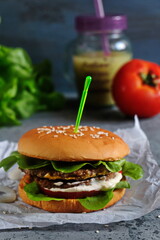 Vegetarian Burger with chickpeas, fresh cucumber, tomato, salad and sour cream sauce. The concept of healthy eating. An alternative to the usual hamburger. Vertical.