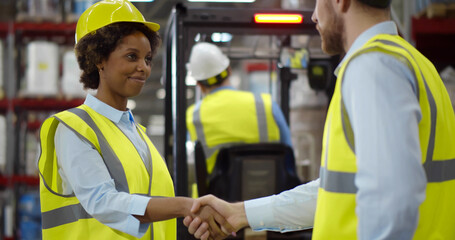 Happy young businessperson making deal with warehouse manager