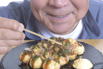 和食のたこ焼きを笑顔で食べるシニア