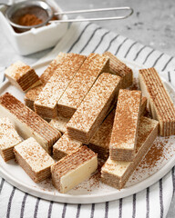 Waffles with chocolate and coffee filling in a white plate on a light background. Lots of wafers on the kitchen table