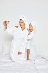 mother and daughter in bathrobe taking selfie by smartphone