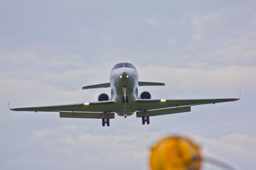 A twin-engine jet airliner is landing with its landing gear extended directly front the camera.