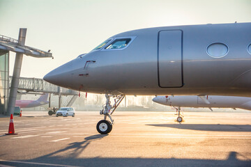 Jet private grey metallic colour aircraft parked at the airport at dawn, Airplane at the airport at sunrise
 