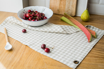 ripe red sweet cherries lying on table in a dish and on linen napkin.