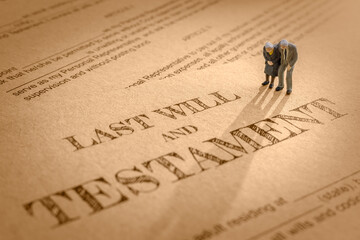 Last will and testament / legacy, inheritance or death tax concept : Miniature elder / old couple stands on a legal document form, depicts preparing to transfer properties to their heirs after death