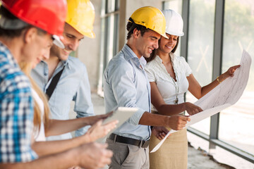 Two architects and engineers looking and discuss with about blueprint and construction project.